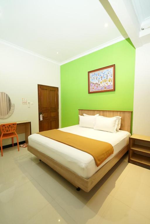 een slaapkamer met een bed met een groene muur bij The Cabin Hotel Ngupasan in Yogyakarta