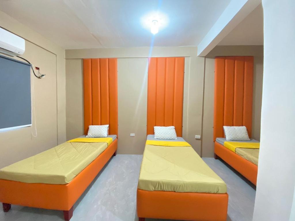 two beds in a room with orange curtains at XYC Hostel in Tinajero