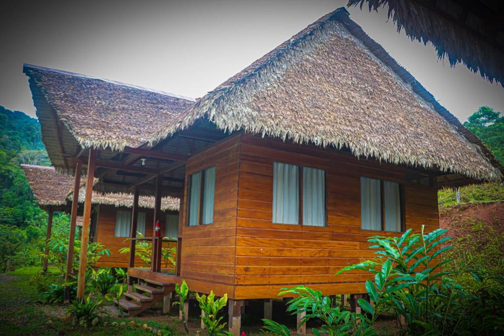 una pequeña casa de madera con techo de paja en Kotsimba Lodge, en Puerto Leguía