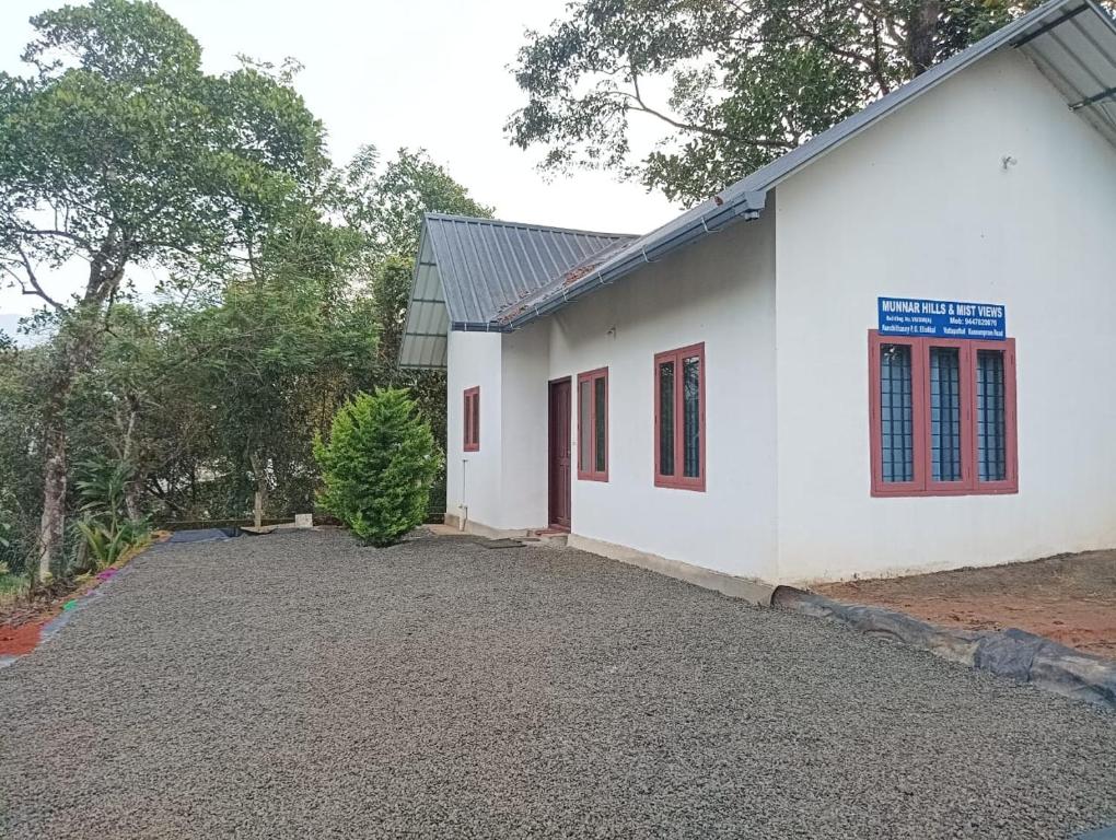 a white building with red windows and a driveway at Munnar Hills & Mist View in Anachal
