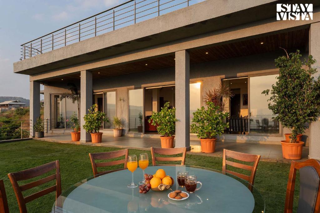 a table with glasses of orange juice and fruit on it at Aarna House by StayVista - Mountain & lakeview villa, Contemporary modern interiors & a charming terrace garden in Pune