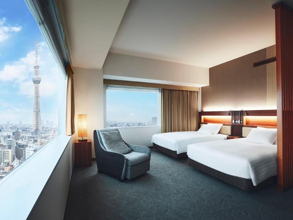 a hotel room with two beds and a chair and a window at Lotte City Hotel Kinshicho in Tokyo