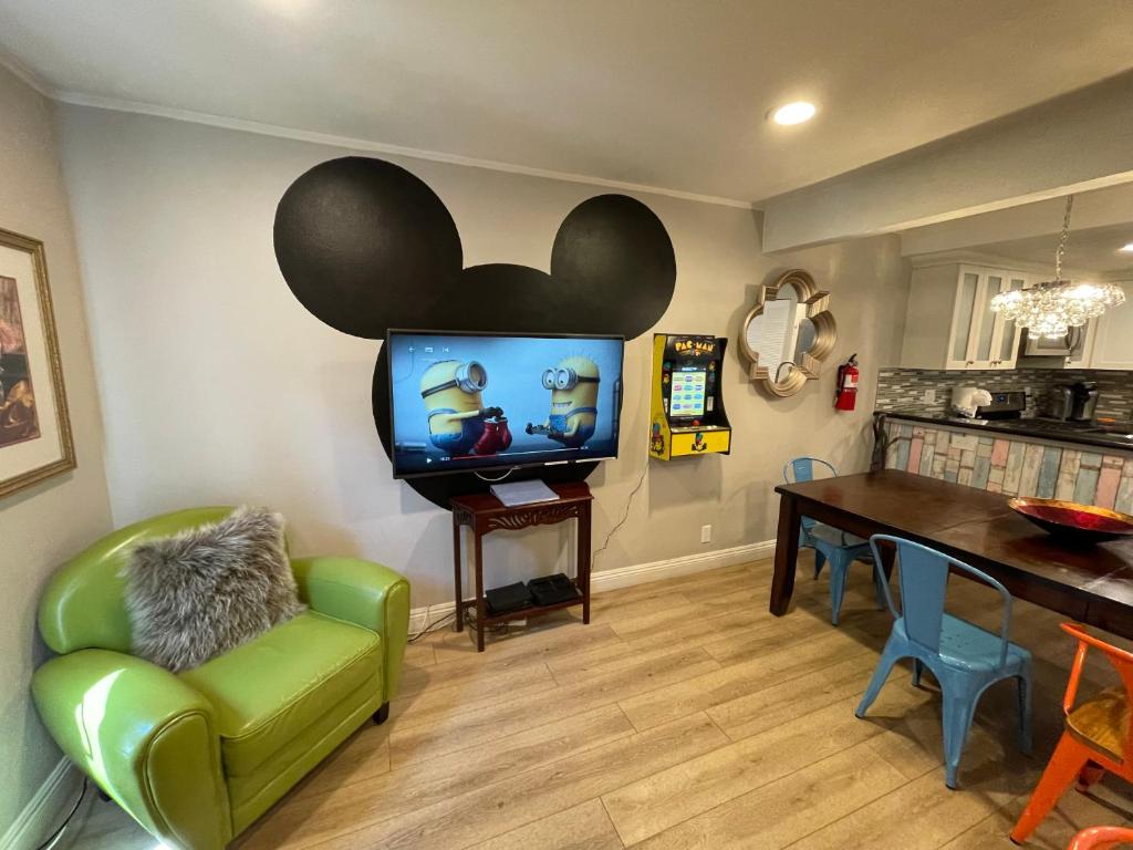 a living room with a tv and a green chair at MAGICAL Xcape, POOLS-SPA, WALK 2 DISNEY, CENTRAL AC-HEAT, FULLY EQUIPPED, 2 FREE PARKING SPACES, OWNER MGMT in Anaheim