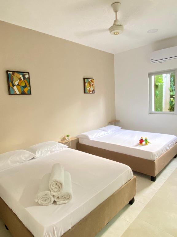 2 camas en una habitación con paredes blancas en Guakmaya hostel, en Cartagena de Indias