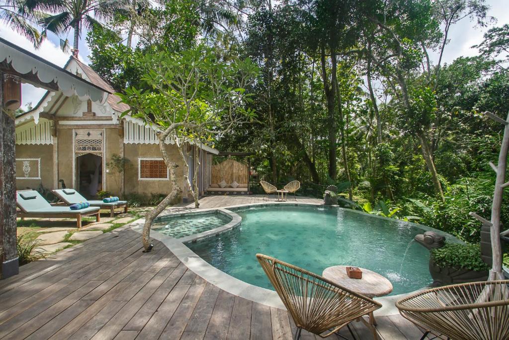 un patio trasero con piscina y terraza de madera en Sacred Beji by Pramana Villas en Payangan