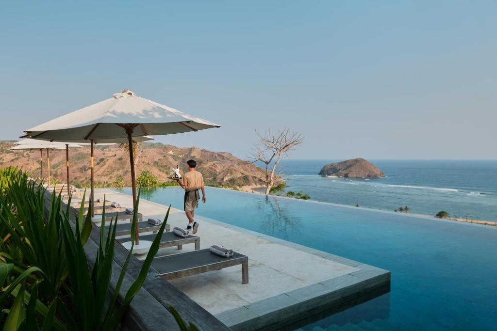 a man standing next to a swimming pool next to the ocean at Somewhere Lombok in Kuta Lombok