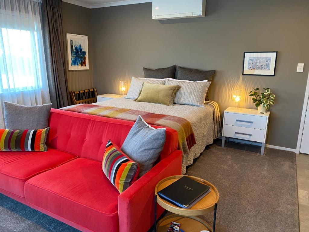 a bedroom with a bed and a red couch at Escape in New Plymouth