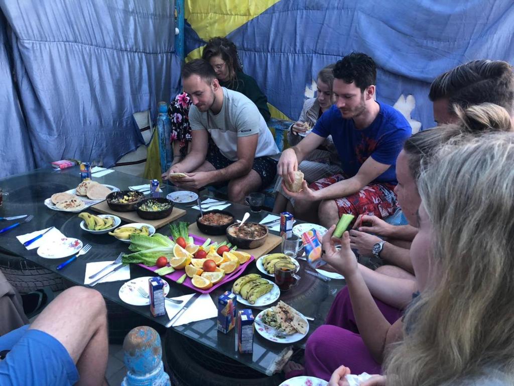 a group of people sitting around a table eating food at Hana hostel in Hurghada