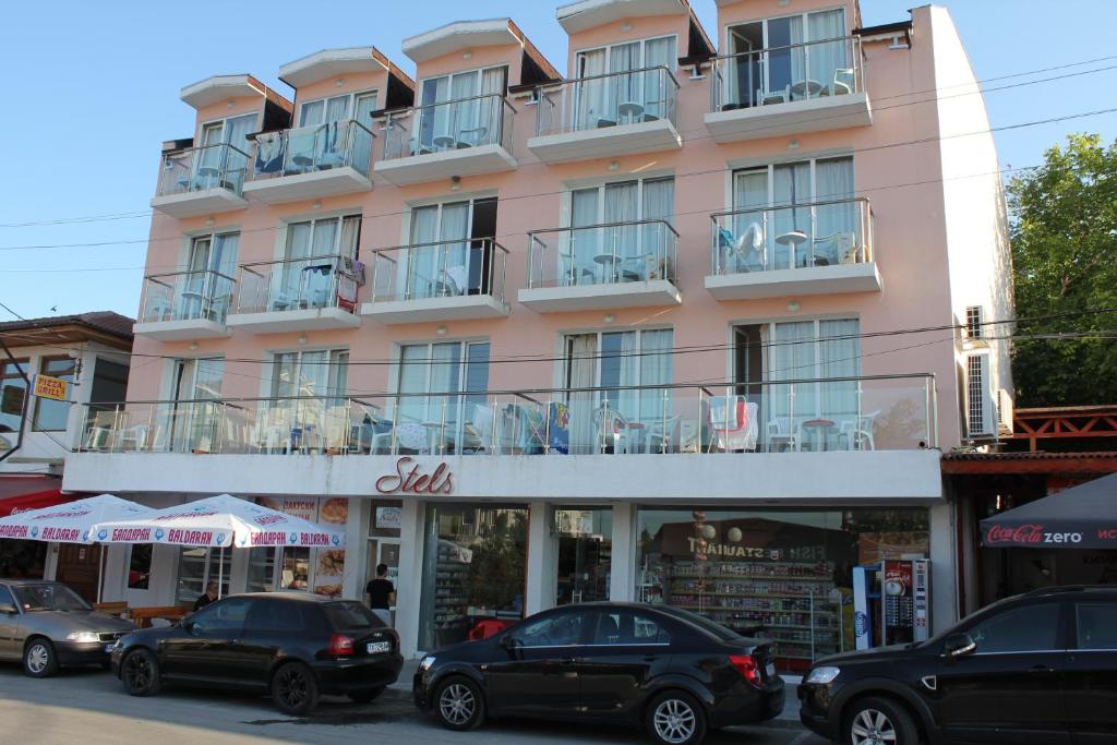 a pink building with cars parked in front of it at Guest House Stels in Kranevo