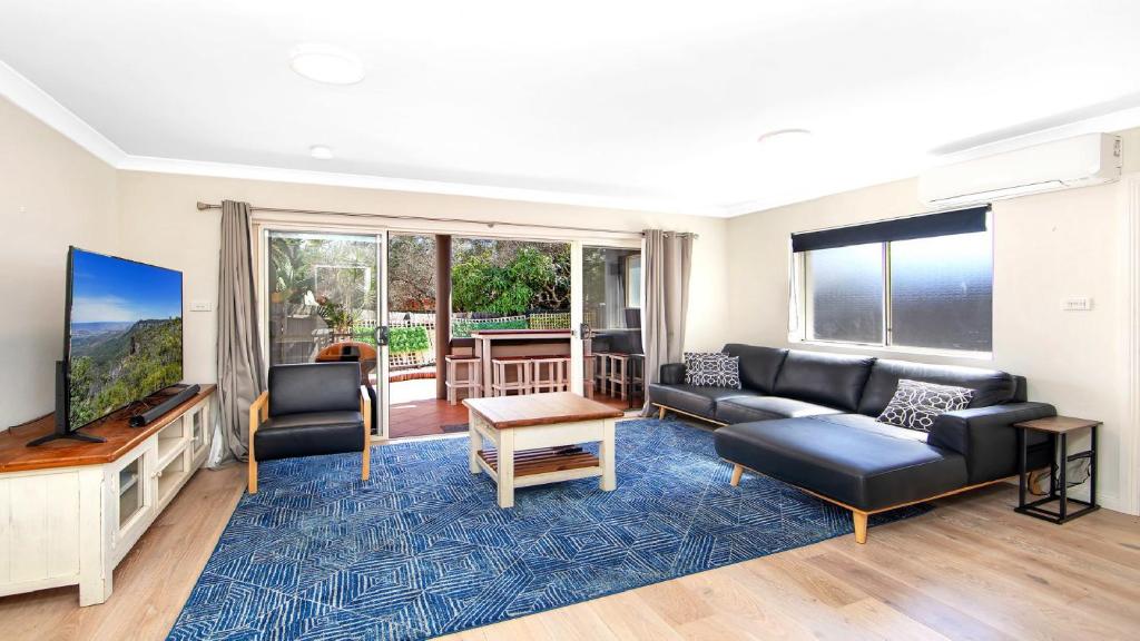 a living room with a couch and a tv at Summer By The Sea Umina Beach in Ettalong Beach