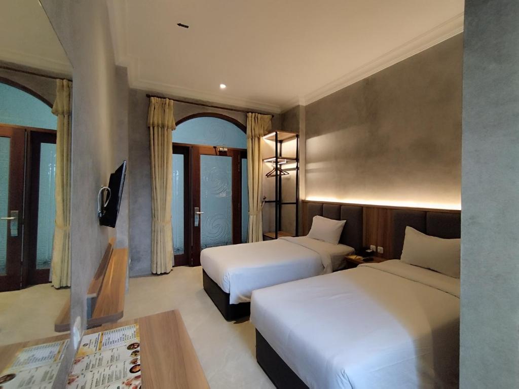 um quarto de hotel com duas camas e uma mesa em The Grand Palace Hotel Malang em Malang