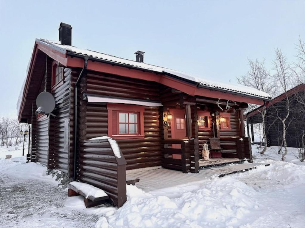 domek z bali na śniegu z werandą w obiekcie Villa Tsahkal Kilpisjärvi w mieście Kilpisjärvi