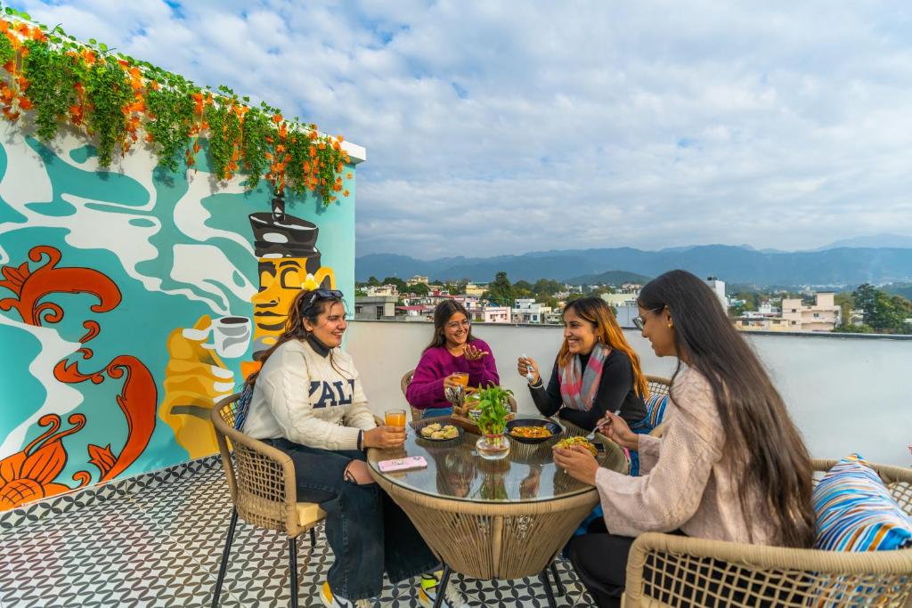 eine Gruppe von Frauen, die um einen Tisch auf einem Dach sitzen in der Unterkunft ArtBuzz Dehradun in Dehradun