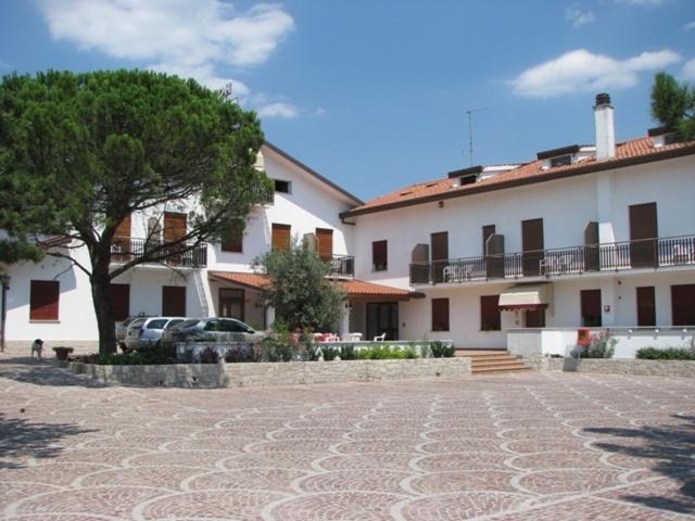 un grand bâtiment blanc avec un arbre en face dans l'établissement Hotel Alla Dolina, à Sistiana