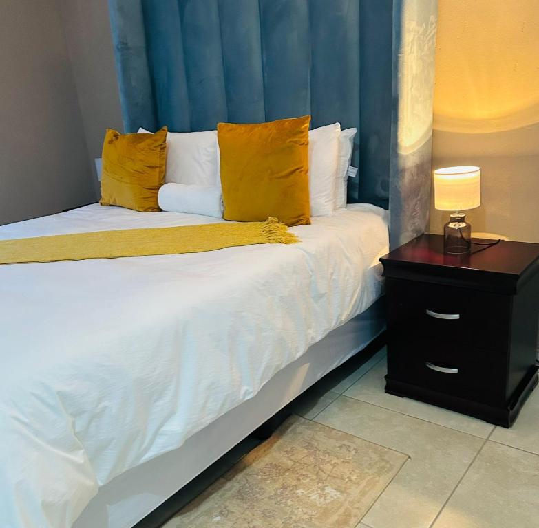 a bedroom with a bed with yellow pillows and a table at SERENE ACCOMMODATION PALACE in Bela-Bela