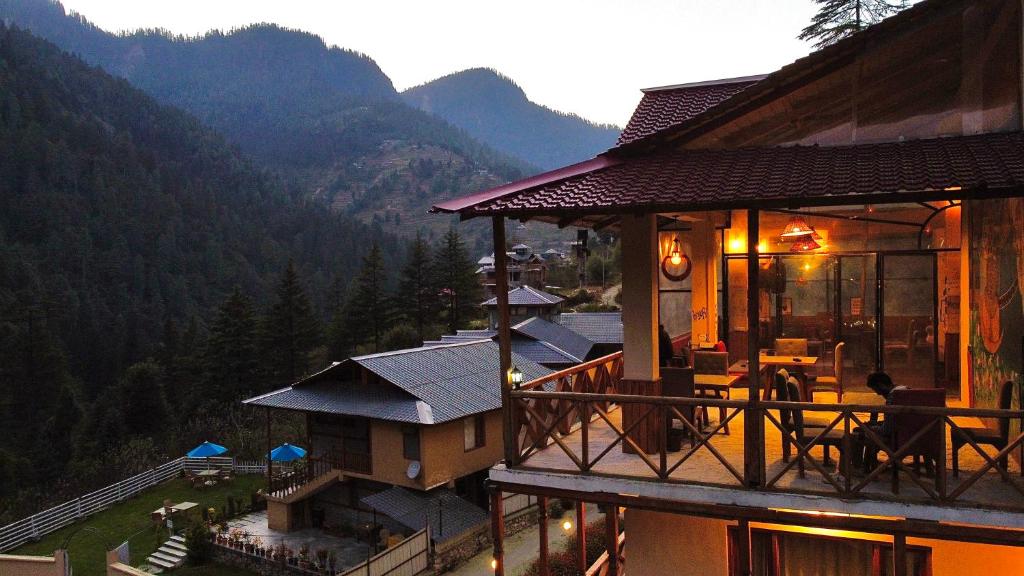 a building with a balcony with a view of mountains at ThePahadians Food & Stay in Jibhi