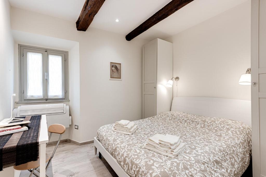 een witte slaapkamer met een bed en een bureau bij Oltrarno Dreaming in Florence