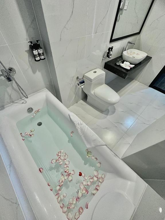 A marble-look bathroom contains a corner whirlpool tub, toilet and countertop basin.