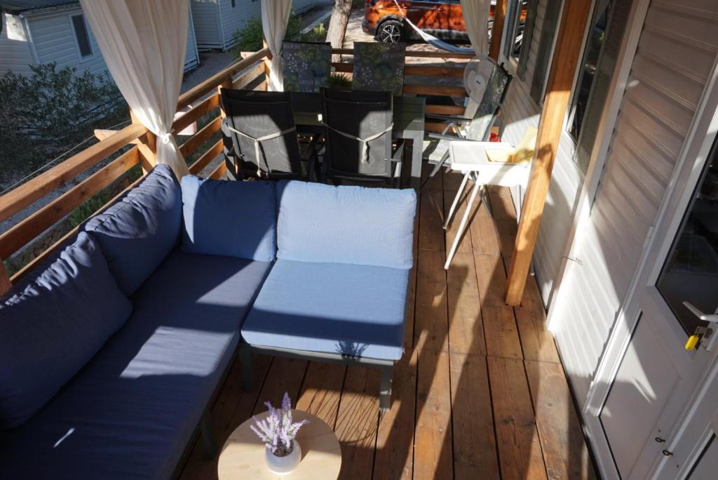 een veranda met een blauwe bank en een tafel bij DM mobile home in Jezera