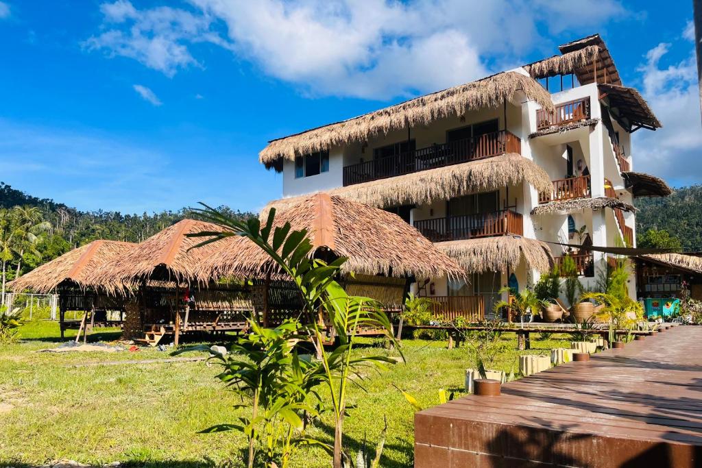 a hotel with thatched roofs and a grass at La Palapa Inn Port Barton in San Vicente