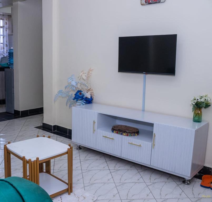a white entertainment center with a flat screen tv on a wall at Tiny Haven executive one bedroom with Private Balcony in Nanyuki