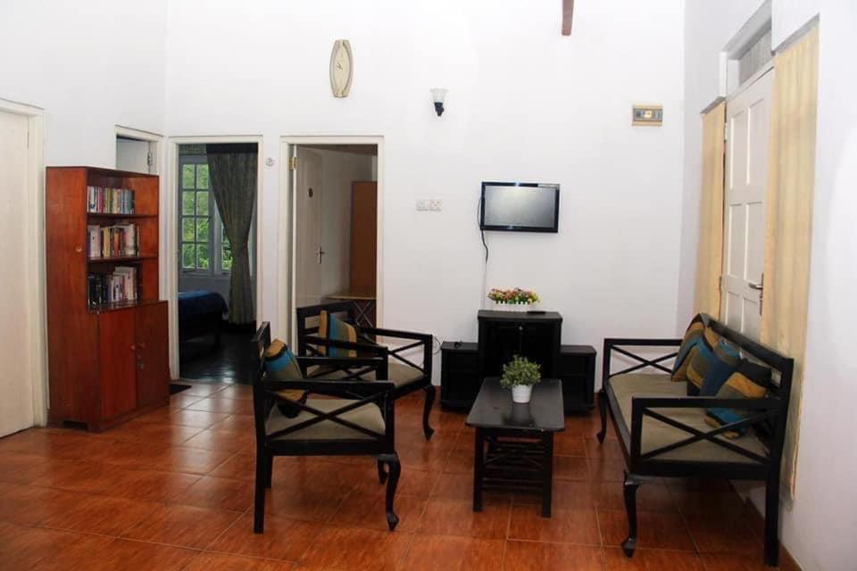 ein Wohnzimmer mit Stühlen, einem Tisch und einem TV in der Unterkunft M country home in Mirahawatta