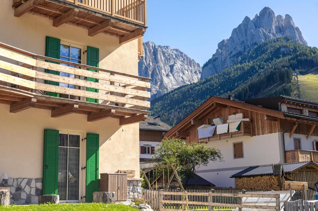 budynek z zielonymi drzwiami i górami w tle w obiekcie Majon de la nona w mieście Pozza di Fassa