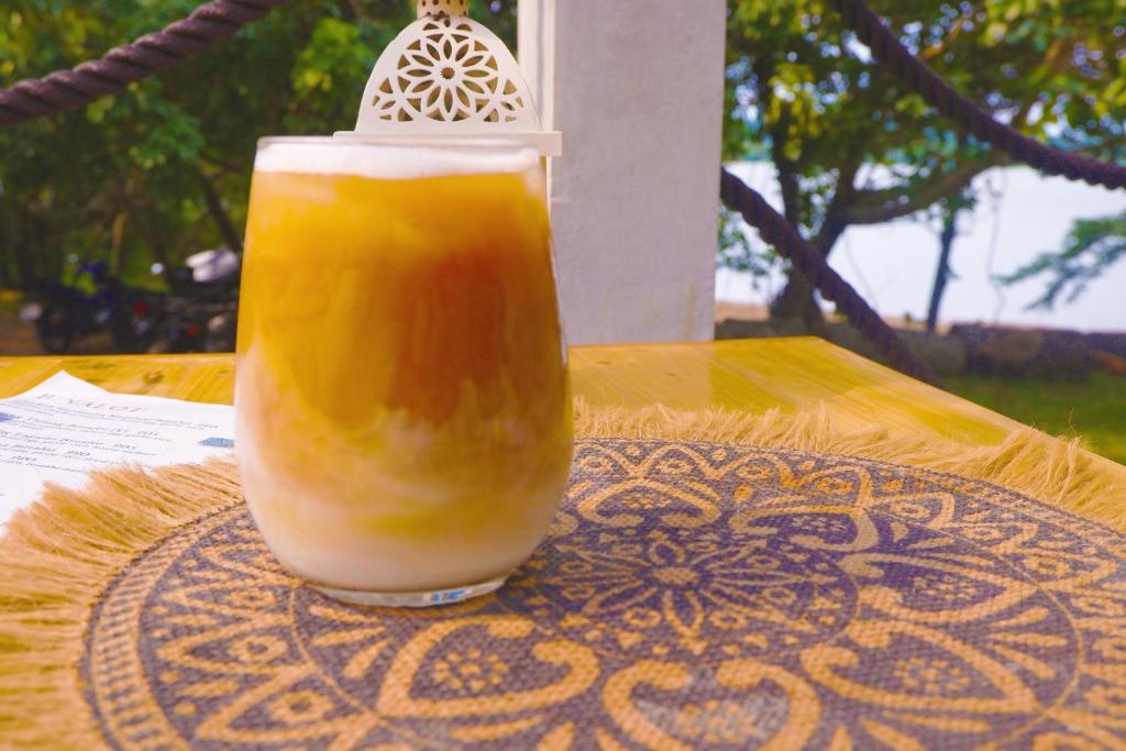 Cavinti的住宿－Kaliraya Surf Kamp by Eco Hotel Laguna，坐在桌子上的一杯橙汁
