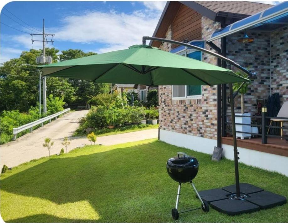 a green umbrella and a grill in a yard at Donghae sea hill House in Yŏngdŏk