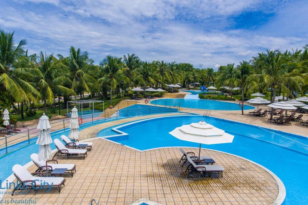einen Pool im Resort mit Liegestühlen und Sonnenschirmen in der Unterkunft Sealink Beach Villa PE48- PE69 in Ấp Bình Hưng