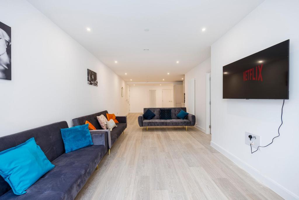 a living room with a couch and a tv on a wall at 2&3 Bedrooms near EXCEL London - Modern Spacious Apartment For Larger Groups in London