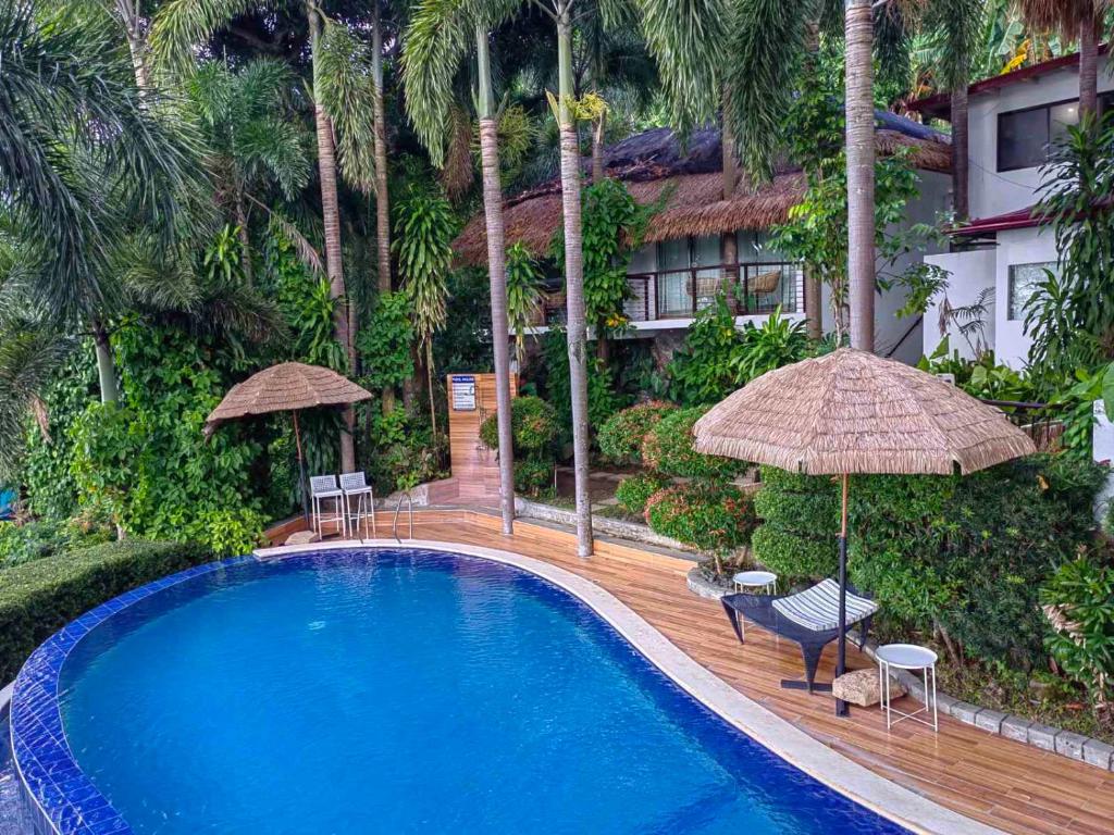 - une piscine avec des chaises et des parasols à côté d'un bâtiment dans l'établissement Villas by Eco Hotels Batangas, à Mataasnakahoy