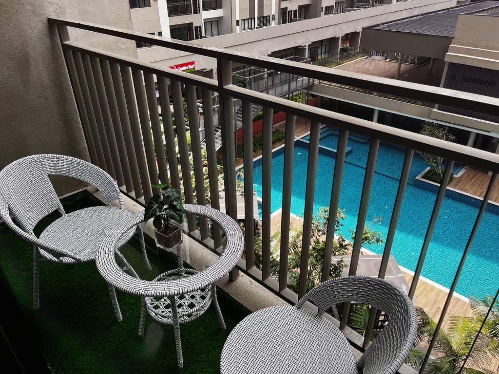 a balcony with two chairs and a table and a pool at Youth City Cozy Pool View Homestay Nilai by TR in Nilai