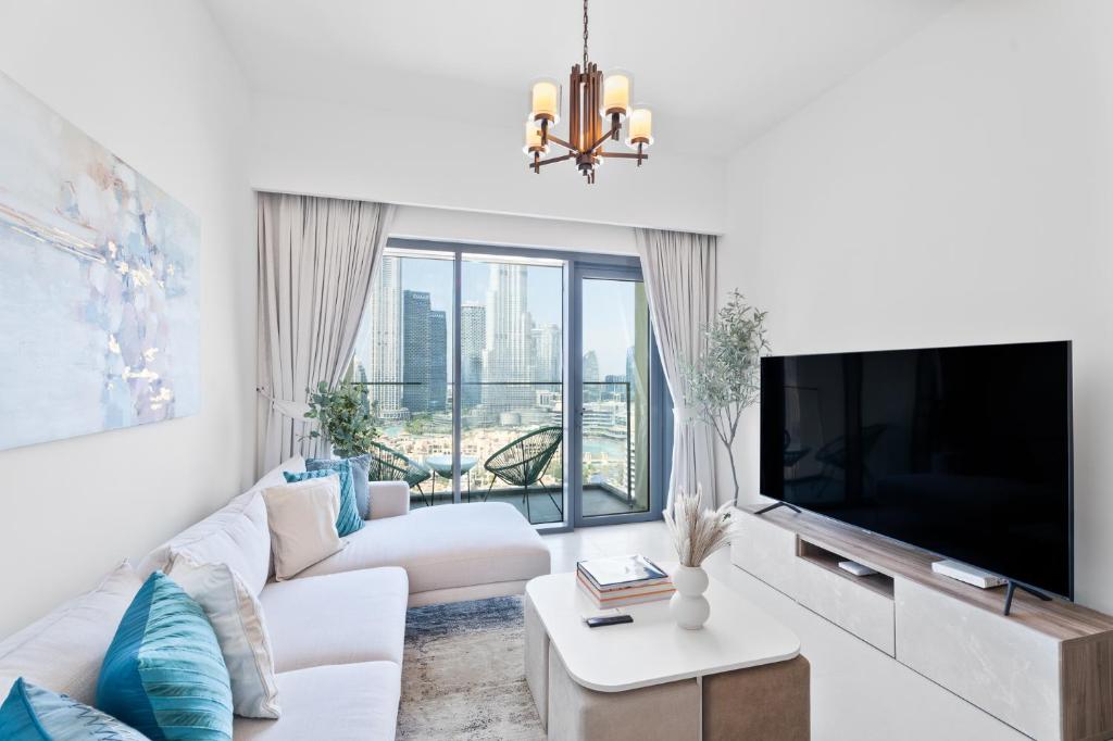 een woonkamer met een witte bank en een grote televisie bij Nasma Luxury Stays - Burj Royale 2BR Apartment in Downtown With Views in Dubai