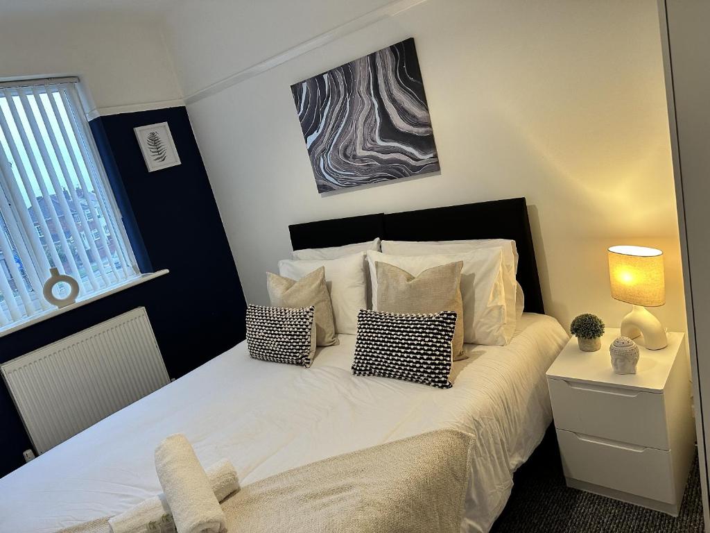a bedroom with a large white bed with pillows at Charming Apartment Near Broad Green Hospital in Liverpool