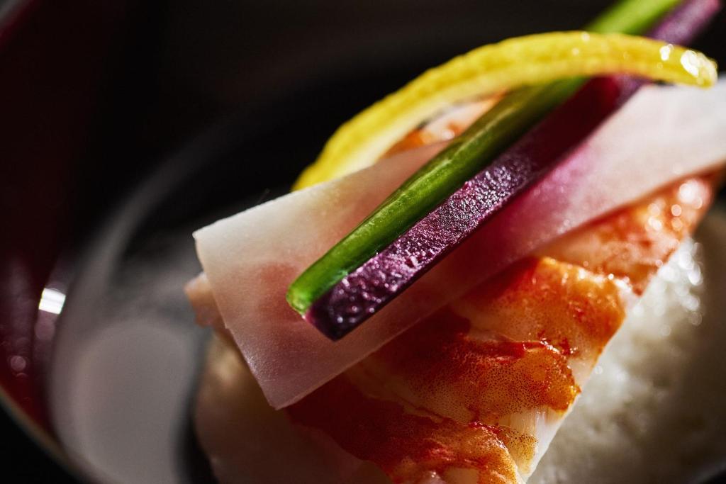 a piece of sushi with a pickle on top of it at Waqoo Naritasanmonzen in Narita
