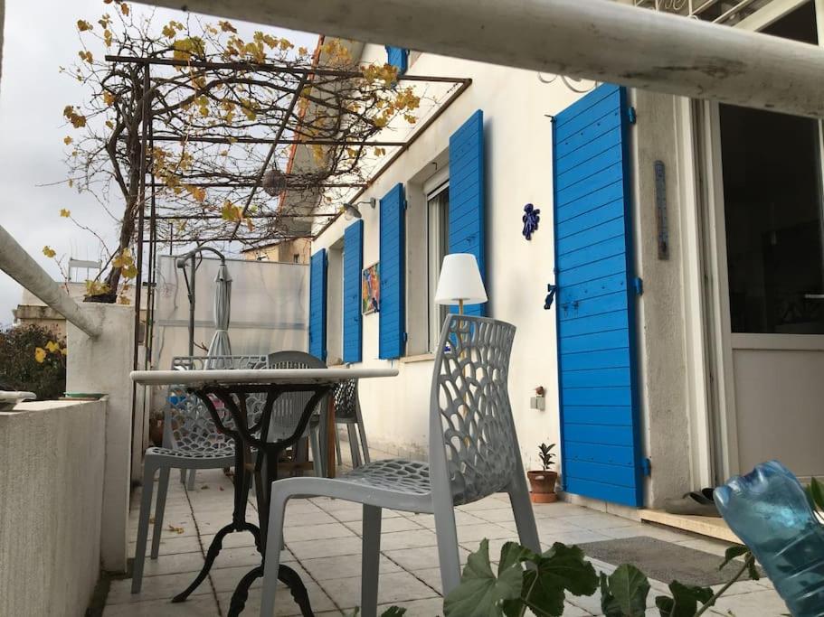 a patio with chairs and a table and blue doors at FLC-Sea View-Jacuzzi-3 Bedrooms-8p-Parking for 2 cars in Marseille