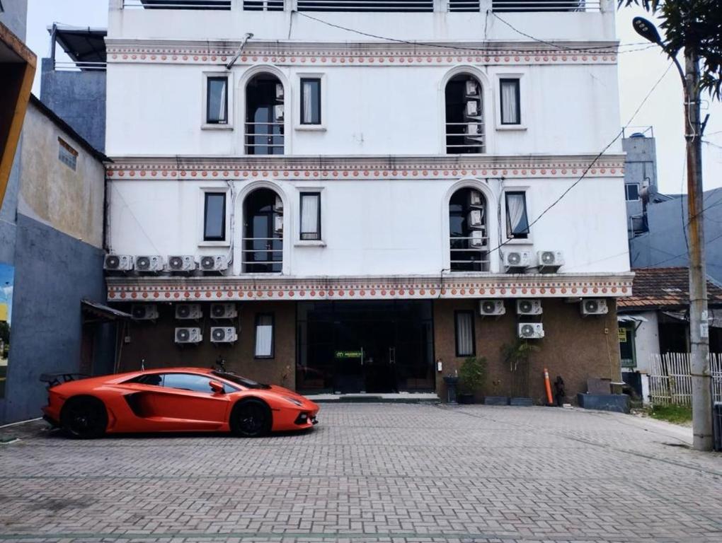 ein rotes Auto, das vor einem Gebäude parkt in der Unterkunft Anugrah Inn in Nalagat