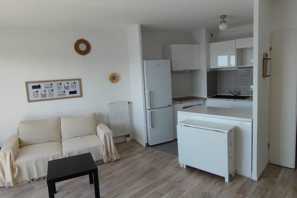 un soggiorno con divano e una cucina di Appartement type T2 proche commodités et gare avec accès direct paris a Éragny