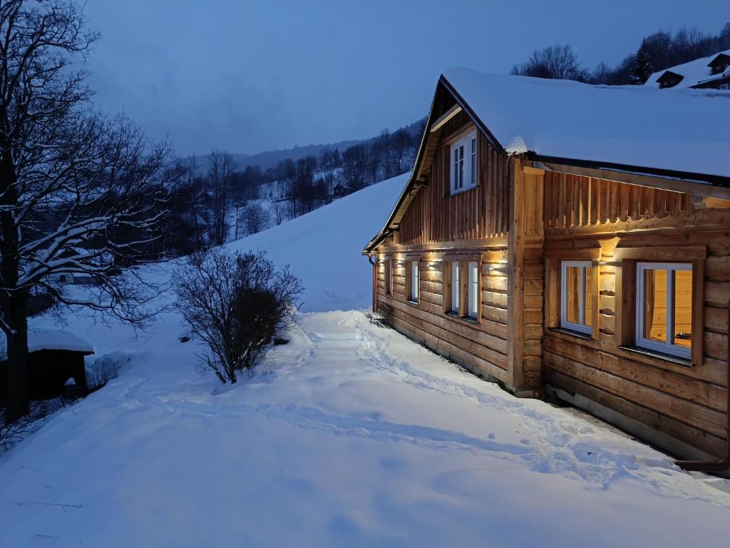 una cabaña de madera en la nieve por la noche en Luční chalupa, en Velká Úpa