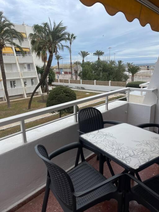 a table and chairs on a balcony with palm trees at Agradable apto a pie de playa in Caleta De Velez