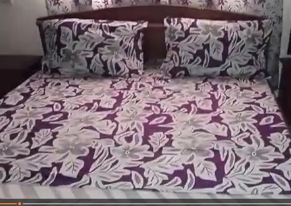 - un lit avec une couverture et des oreillers violets et blancs dans l'établissement Résidences Lili, à Douala