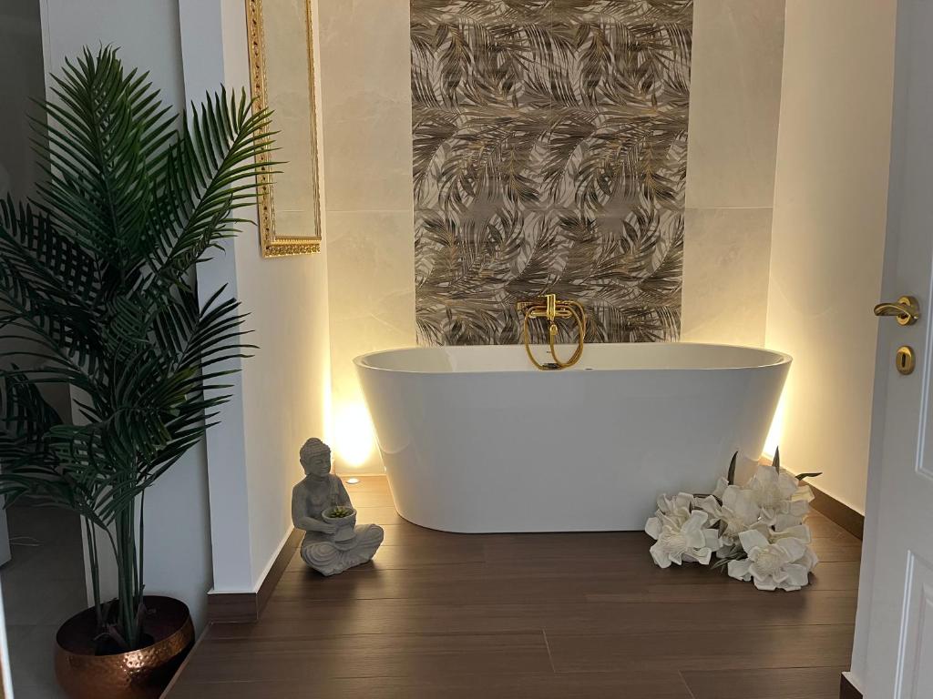 een badkamer met een wit bad en een potplant bij B&B Euthalia in Riposto