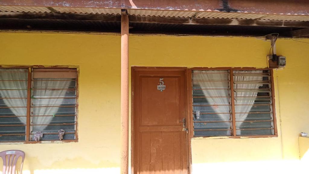 une maison jaune avec une porte et deux fenêtres dans l'établissement Homestay Hajah Zainab Linggi Negeri Sembilan, 