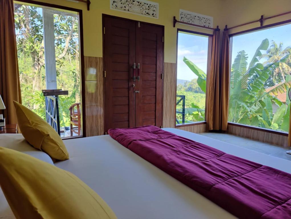 uma cama grande num quarto com janelas grandes em Alamku Bungalow em Tirtagangga