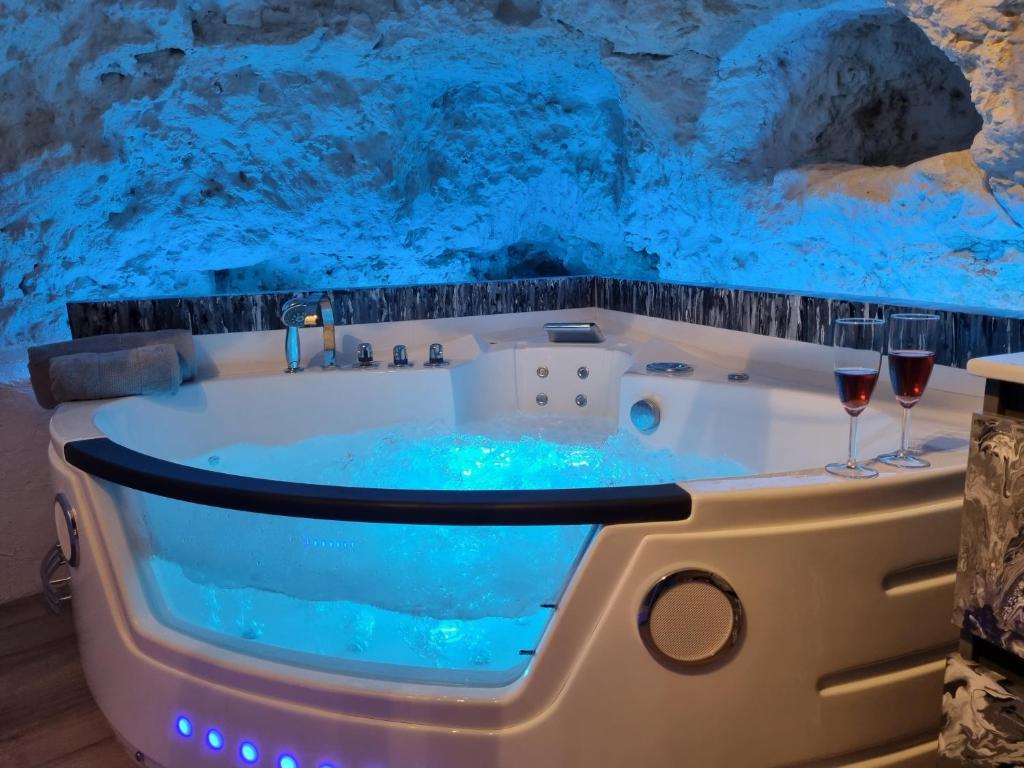 a bathtub in a cave with two glasses of wine at Le clos des violettes in Amboise