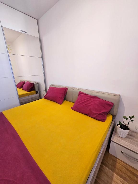 Schlafzimmer mit einem Bett mit gelben und roten Kissen in der Unterkunft Boutique apartman Dora zuto pace in Konik