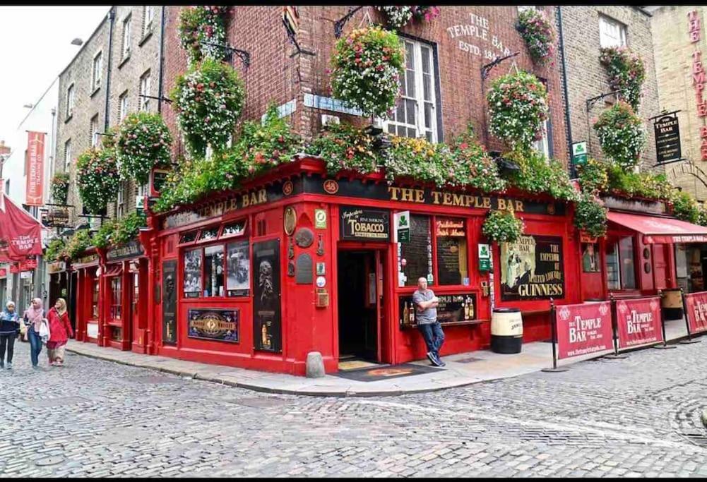 a red building on a street with people standing outside at In Dublin's Best Tourist Spot Temple Bar in Dublin