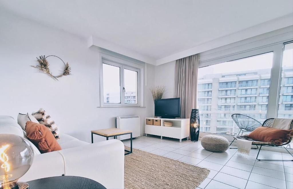 a living room with a white couch and a tv at Shorebreak Nieuwpoort near the beach in Nieuwpoort-Bad