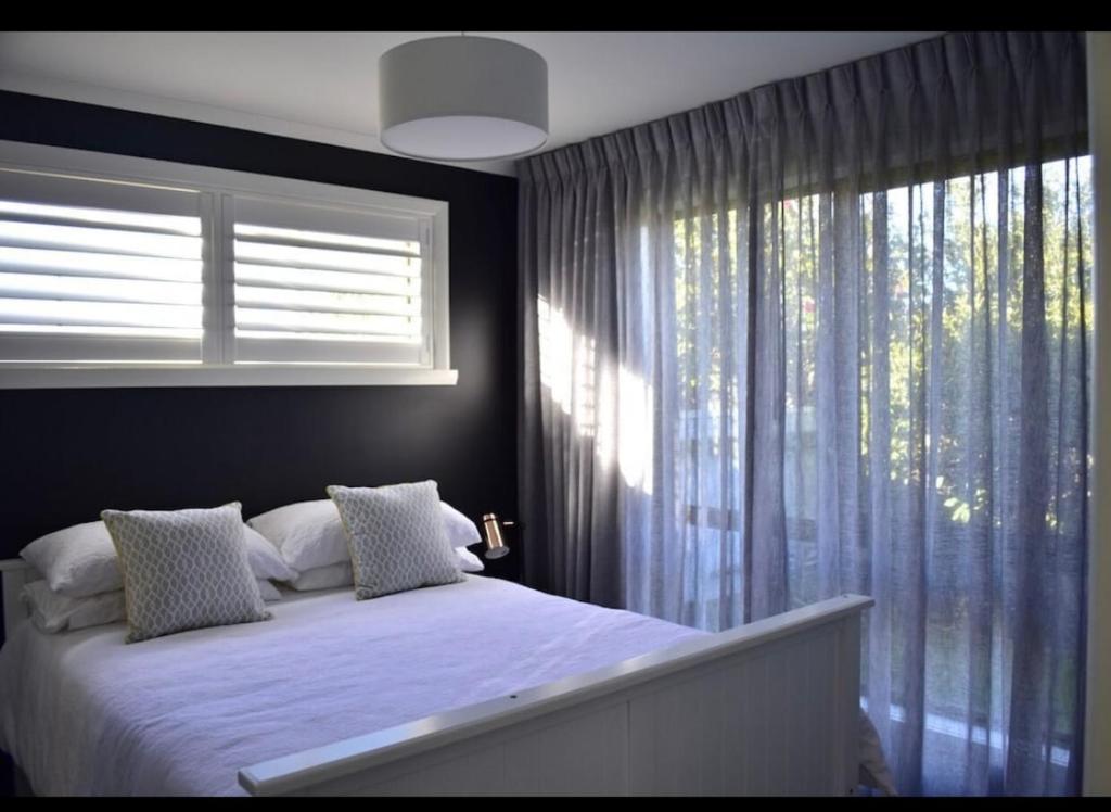 a bedroom with a bed and a large window at Inspire Boutique Apartments in Devonport